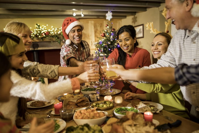 Foto colorida de pessoas brancas e pardas brindam sobre uma mesa cheia de pratos - Metrópoles
