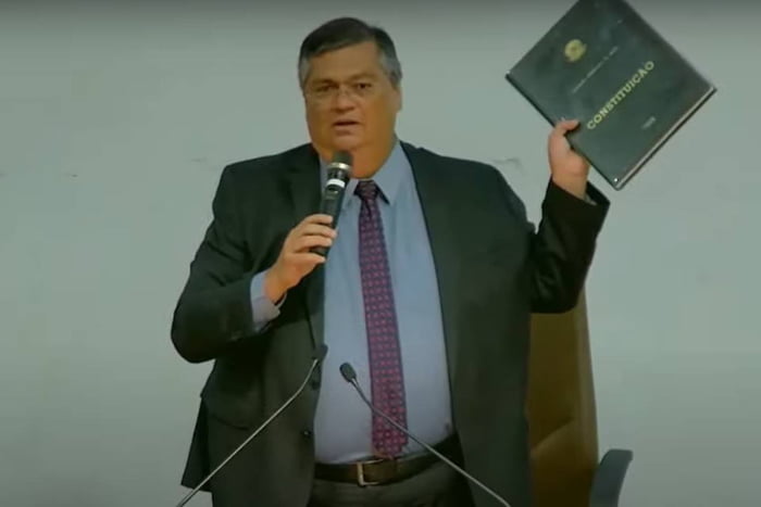 ministro Flávio Dino de terno e segurando cópia da Constituição - Metrópoles