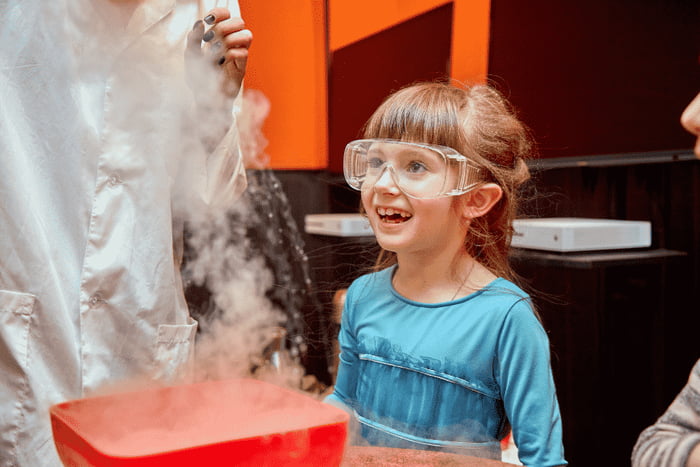 Foto colorida de menina olhando a preparação de doce com nitrogênio