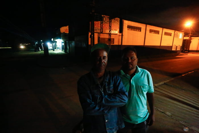 Dois homens em rua à noite olhando para cima