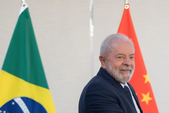 Imagem colorida de Lula com as bandeiras brasileira e chinesa ao fundo