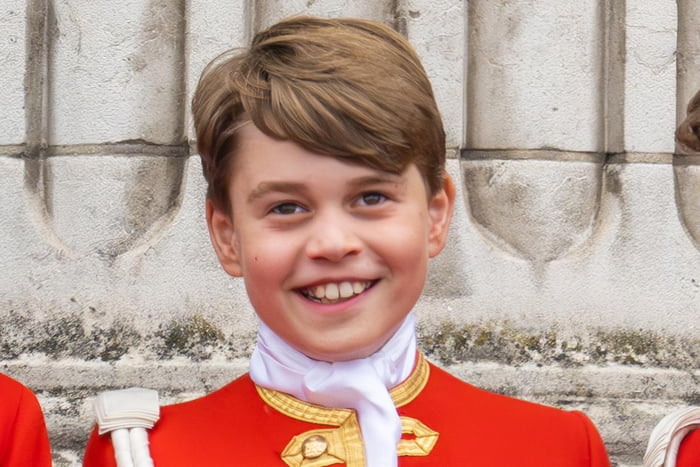 Foto colorida. George é um menino de 10 anos, branco e de cabelos loiros. Na imagem ele está usando um traje formal vermelho e sorrindo - Metrópoles