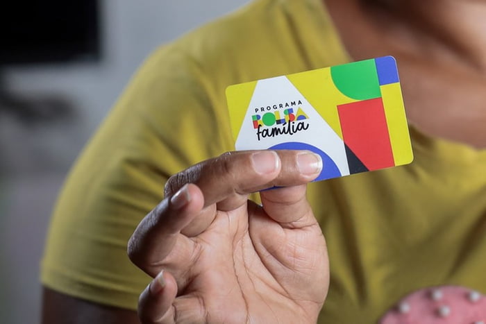 Mulher colorida com Pessoa mostra cartão do Bolsa Família - Metrópoles