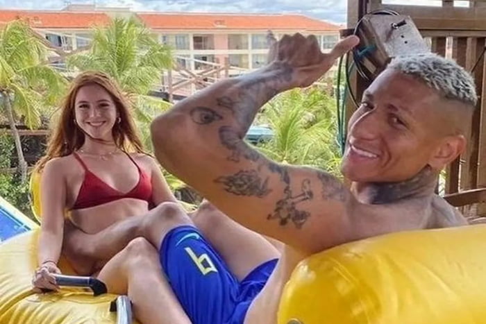 Foto colorida de Amanda Araújo e Richarlison. Ela é ruiva e está de biquíni vermelho, enquanto ele está sem camisa e de shorts da Seleção Brasileira - Metrópoles