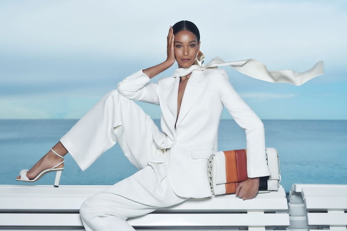 Em cenário na Riviera Francesa, modelo usa look branco de alfaiataria com lenço no pescoço ao vento - Metrópoles
