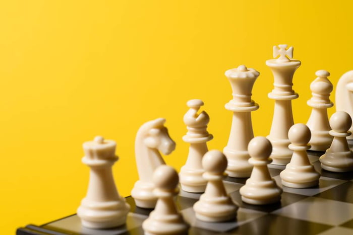 Foto colorida em close de um tabuleiro de xadrez com peças bege em um fundo amarelo - Metrópoles