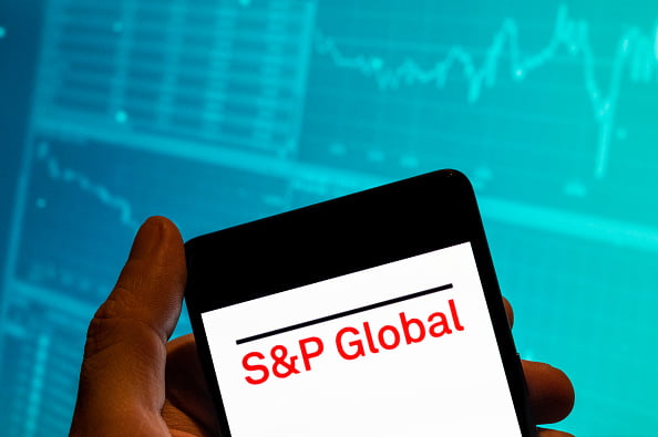 Imagem de um aparelho celular sendo segurado. Na tela, o logotipo da S&P Global, em letras vermelhas - Metrópoles