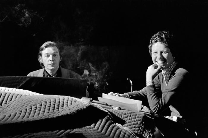 Foto em preto e branco de Tom Jobim e Elis Regina. Eles estão próximos a um piano - Metrópoles