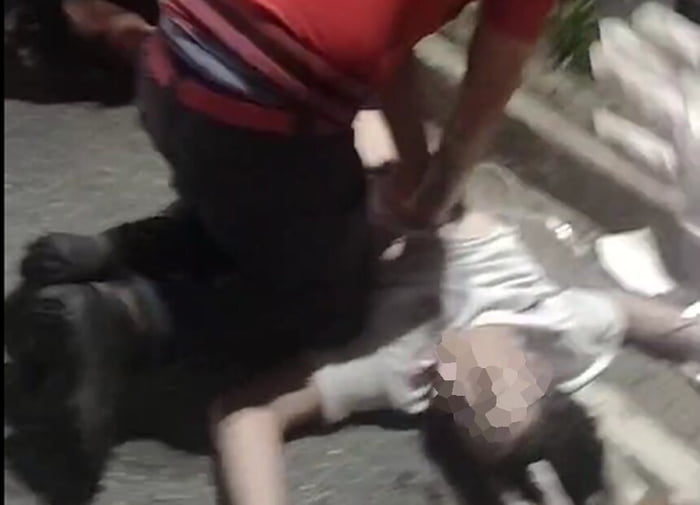 Em foto colorida bombeiro civil faz massagem cardíaca em jovem de amisera branca caído na rua - Metrópoles