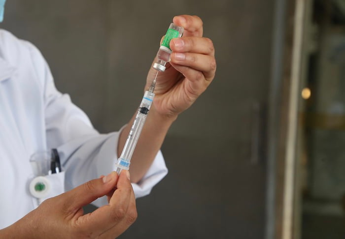Imagem colorida de mãos segurando uma seringa e um recipiente com imunizante - Metrópoles - vacinas