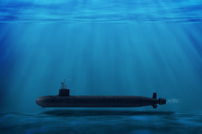 Imagem de um submarino da cor preta no fundo do mar, uma imensidão azul - Metrópoles