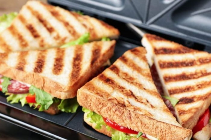 Sanduiche em uma sanduicheira recheado com salada e queijo