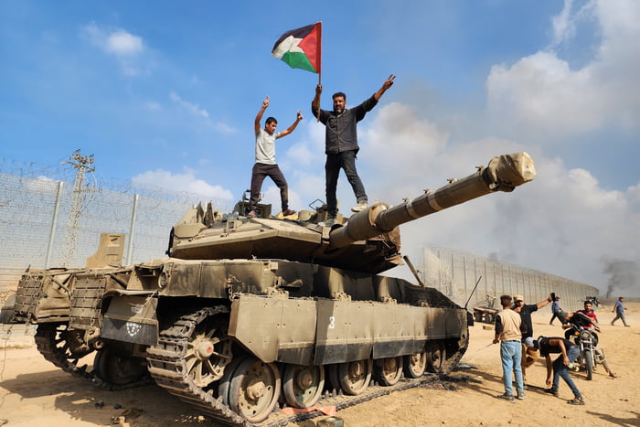 O braço armado do Hamas, as Brigadas Izz ad-Din al-Qassam seguram uma bandeira palestina enquanto destroem um tanque das forças israelenses na Cidade de Gaza