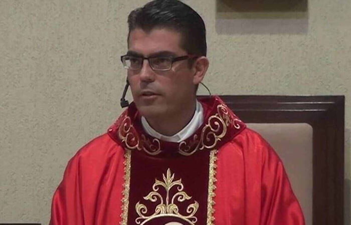 Imagem colorida mostra o padre Ferdinando Henrique Pavan Rubio, um homem branco de óculos de grau, vestido com roupas vermelhas dentro de uma igreja - Metrópoles