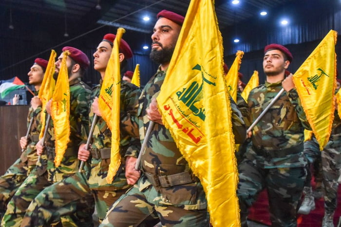 Imagem colorida mostra combatentes do Hezbollah segurando bandeiras do grupo islâmico - Metrópoles