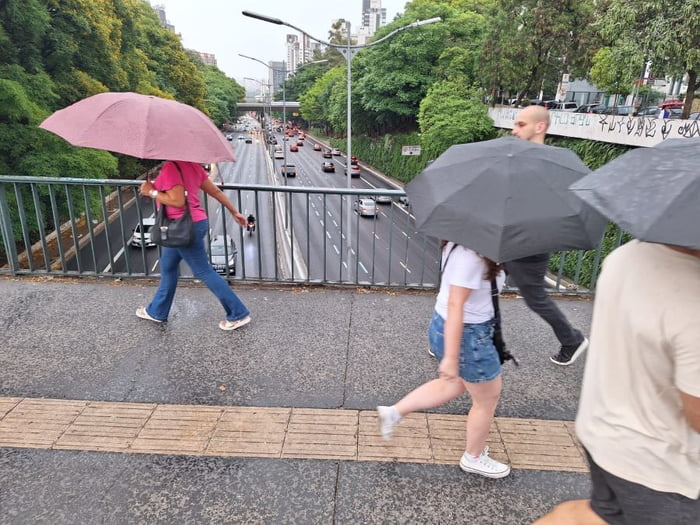 Imagem mostra pessoas caminhando com guarda-chuva - Metrópoles