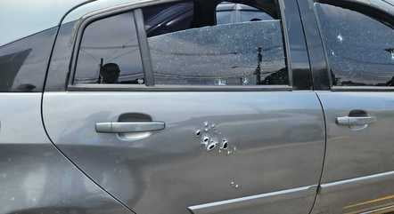 Imagem colorida de lateral de carro cinza com marcas de tiro; um corpo foi encontrado dentro do veículo - Metrópoles