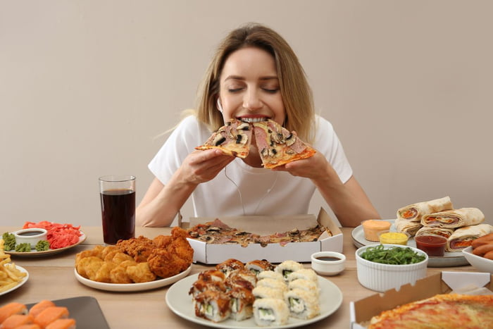 mulher comendo sentada, com duas fatias de pizza na mão