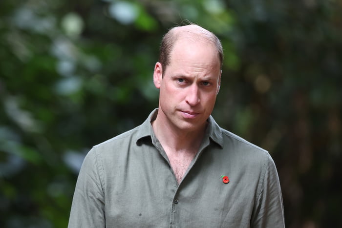 Príncipe William, um homem branco, meio meio calvo, está usando uma camisa verde militar e olhando sério para frente - Metrópoles