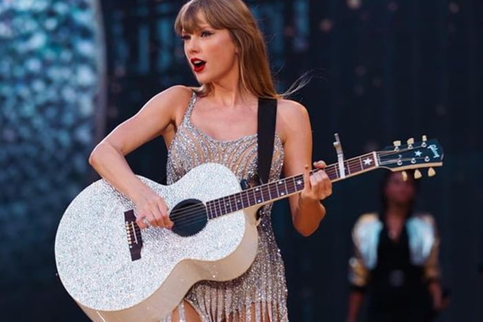 Taylor Swift é clicada tocando violão durante uma de suas apresentações - Metrópoles