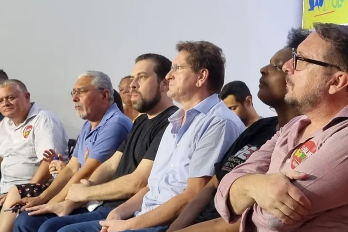 Imagem colorida mostra grupo de homens brancos sentados um ao lado do outro. No meio, de camisa preta, está guilherme boulos - Metrópoles