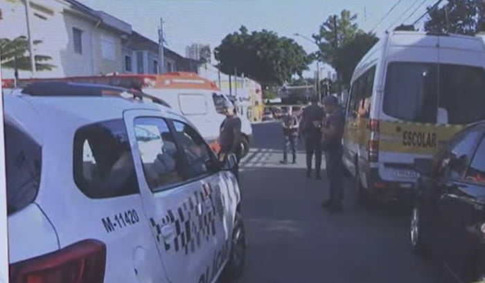 Imagem colorida mostra policiais em volta de uma van escolar onde uma criança foi encontrada morta - Metrópoles