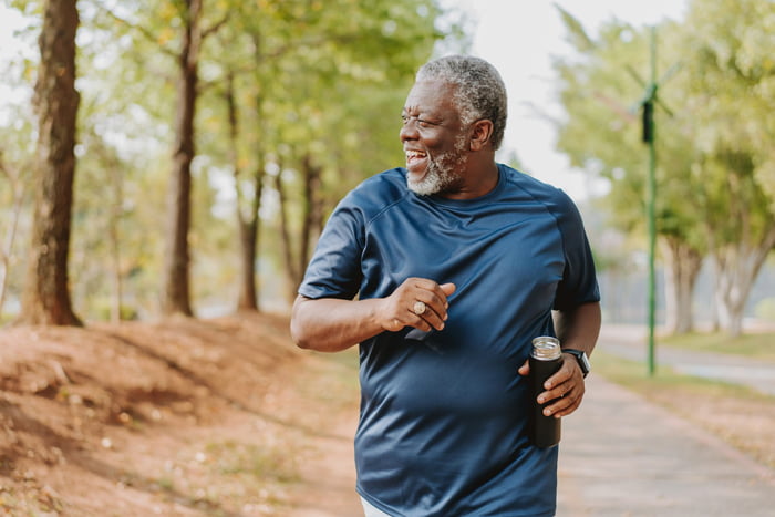 Foto mostra idoso correndo ao ar livre em parque. Envelhecendo bem
