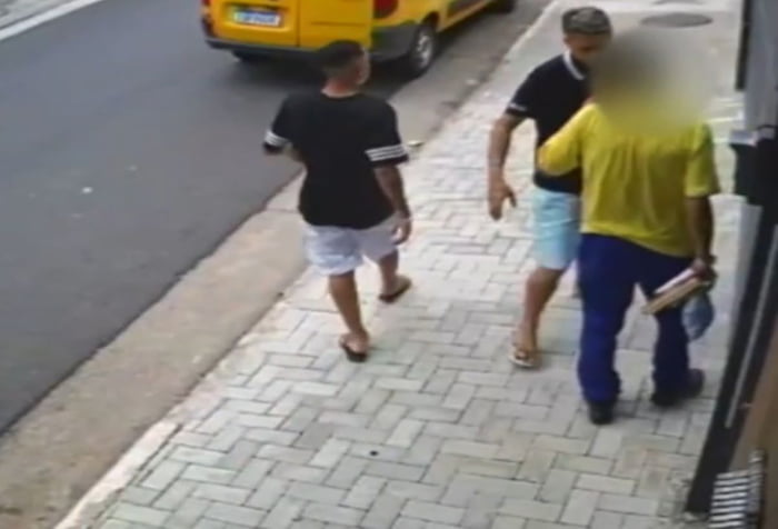 Imagem de dois homens ameaçando funcionário dos Correios em calçada - Metrópoles