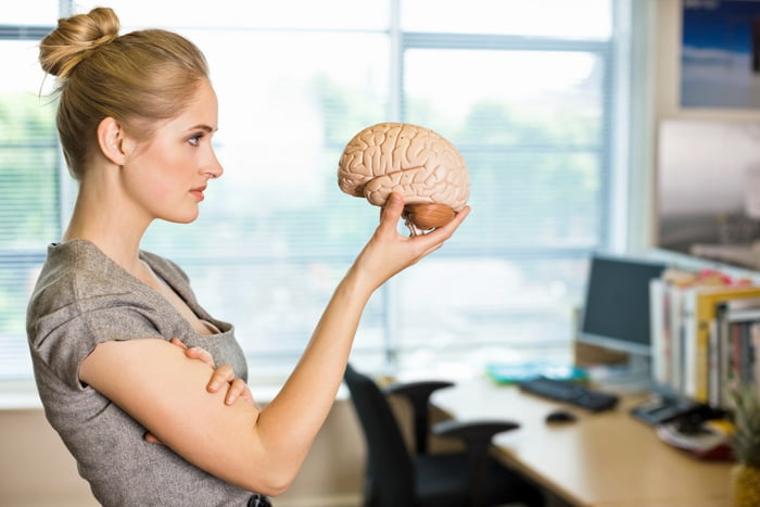 Jovem mulher loira segurando um cérebro de plástico - Metrópoles