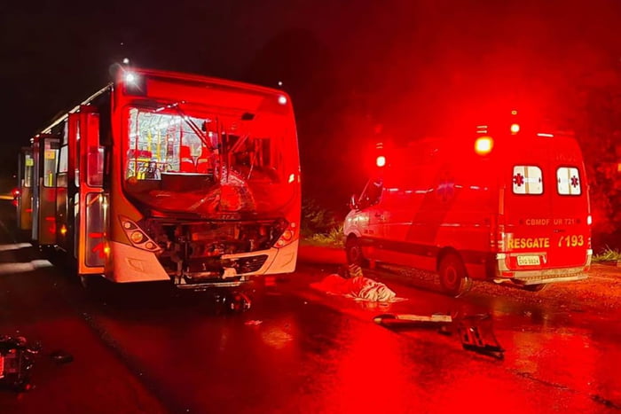 foto avermelhada de onibus batido ao lado de viatura dos bombeiros e corpo no chão coberto com lençol - metrópoles
