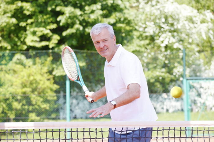 Imagem colorida de idoso jogando tênis em dia ensolarado - Metrópoles