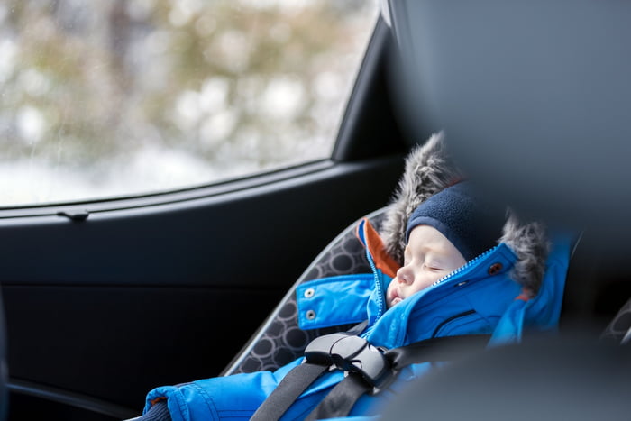 Imagem colorida de bebê dormindo no assento do carro