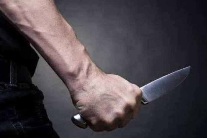 Foto colorida de homem com mão branca segurando uma faca