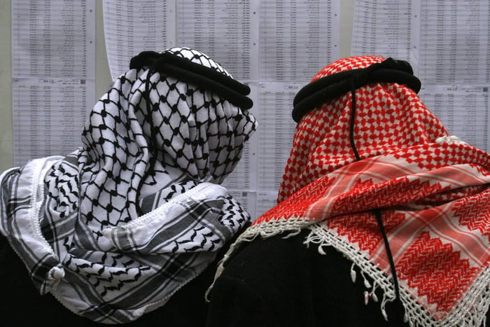 Imagem colorida mostra dois homens de costa usando lenço árabe tradicional - Metrópoles