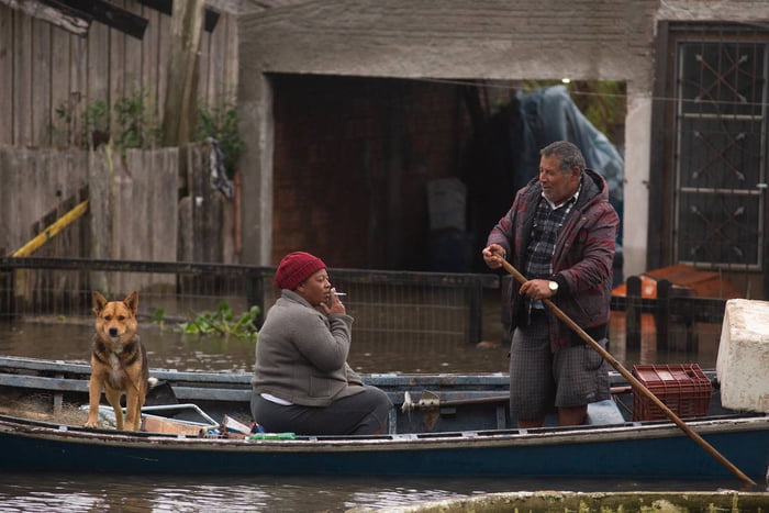 Imagem colorida de duas pessoas e cachorro em canoa, em Pelotas